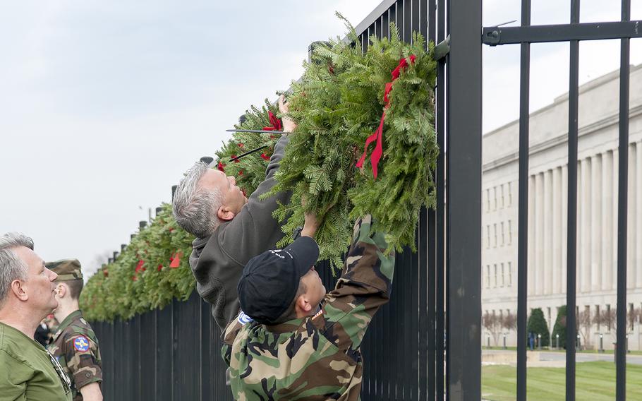 Volunteers help hang wreaths at the Pentagon in Arlington, Va., on Friday, Dec. 11, 2015. The wreaths honored the 184 victims who died on Sept. 11, 2001, when a hijacked aircraft was crashed into the side of the Pentagon.