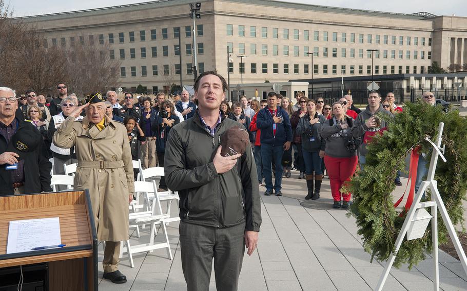 Tobin Slaven, a publicist for Wreaths Across America, leads a crowd gathered at the Pentagon in saying the Pledge of Allegiance before the start of a wreath-hanging event at the Defense Department's headquarters in Arlington, Va., on Friday, Dec. 11, 2015. The wreaths honored the 184 victims who died on Sept. 11, 2001, when a hijacked aircraft was crashed into the side of the Pentagon.