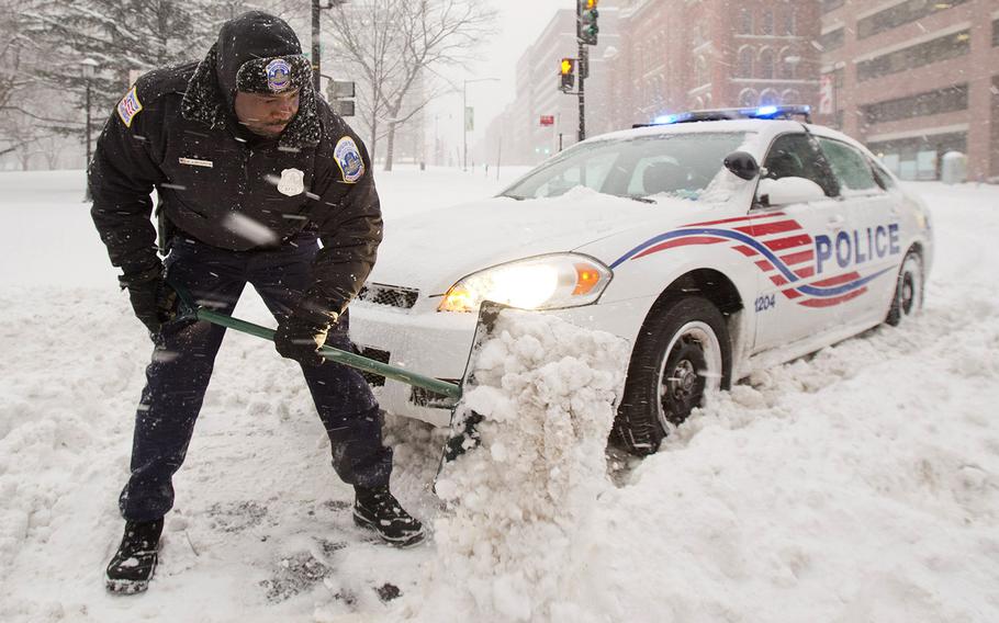 Washington, D.C. Metropolitan Police Officer W.J. Peterson shovels snow to free his vehicle Saturday, Jan. 23, 2016.