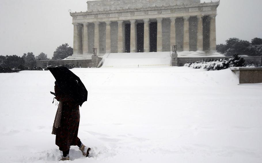 Jasmine Wang walks in front of the Lincoln Memorial in the snow, Saturday, Jan. 23, 2016 in Washington, D.C.
