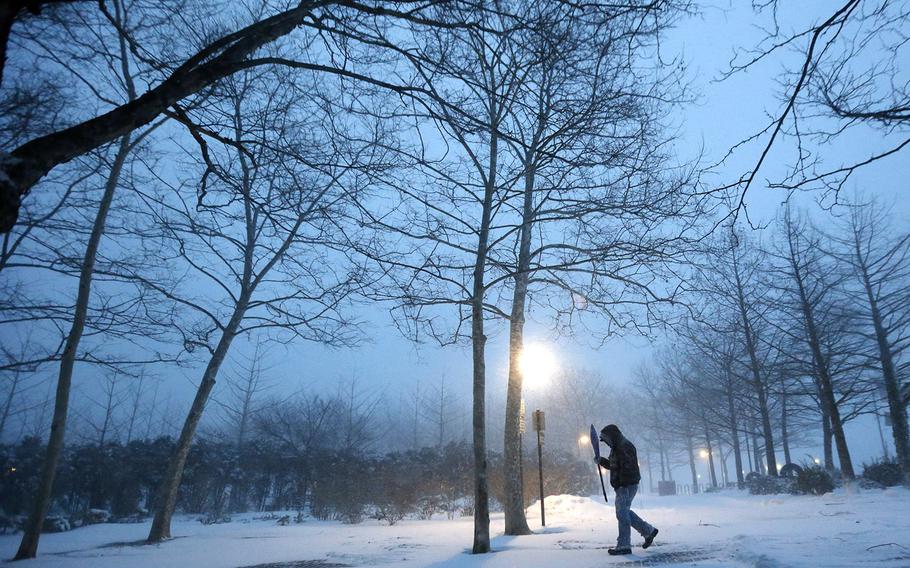 Hoboken, N.J. city employee Edwin Lopez uses a snow shovel to block the sideways-blowing snow from his face while cleaning up a walking path at Pier A Park during a snowstorm, Saturday, Jan. 23, 2016.