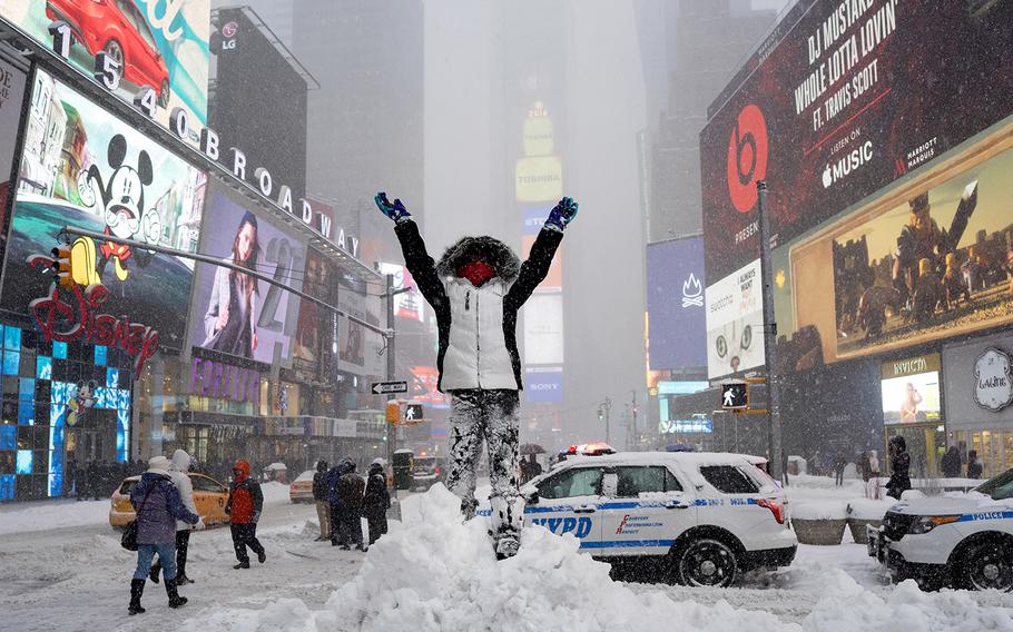 Bella Fraker, 10, of Atlanta, stands high on a snow pile as she poses for a family photo in New York's Times Square Saturday, Jan. 23, 2016.