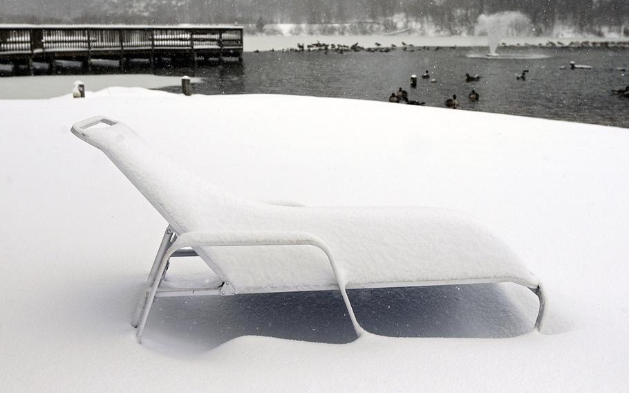 A pool chair is covered in snow on the bank of the lake at Lakeside Apartments as snow continues to fall in Charlottesville, Va. on Saturday, Jan. 23, 2016.