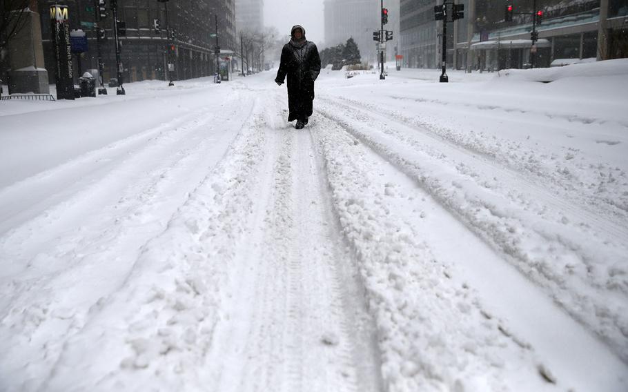 Donna Brown of Germantown, Md., walks in the street on her way to work in downtown Washington, D.C., Saturday, Jan. 23, 2016.