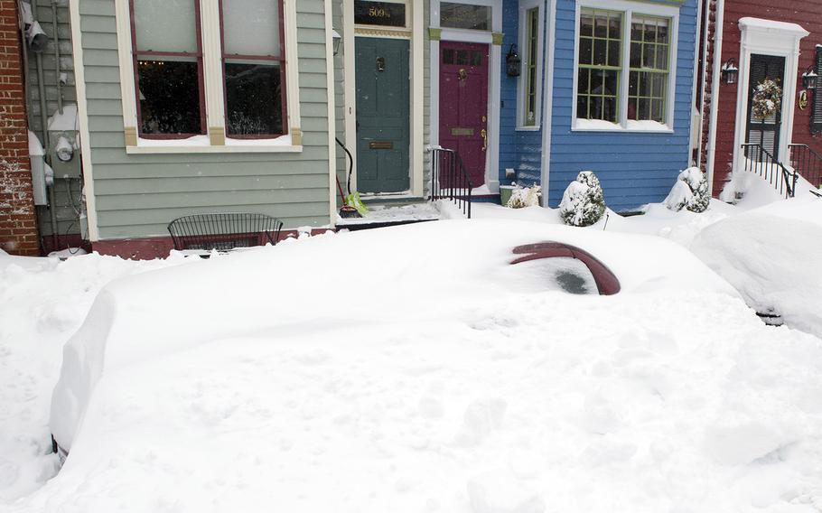 A car is buried under snow on a residential street in Alexandria, Va., Saturday, Jan. 23, 2016.
