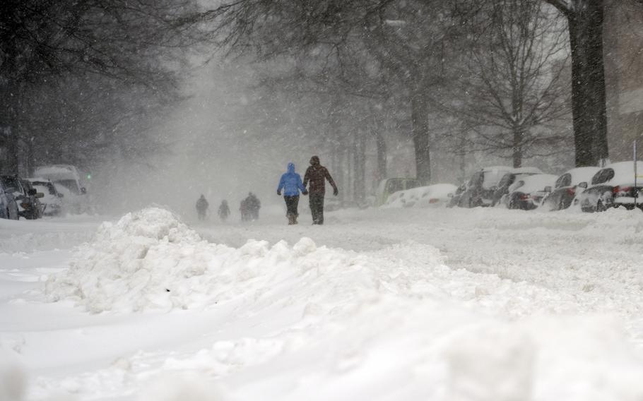 People walk along a deserted street on Jan. 23., 2016, in a residential area of Washington, D.C., during the blizzard.