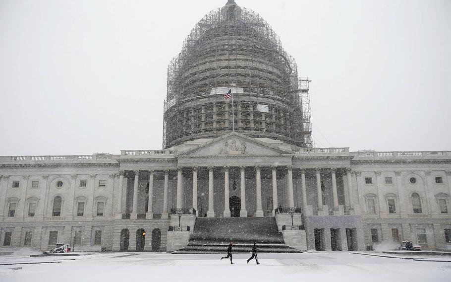 Two runners jog as the snow falls on Capitol Hill, Friday, Jan. 22, 2016, in Washington. 