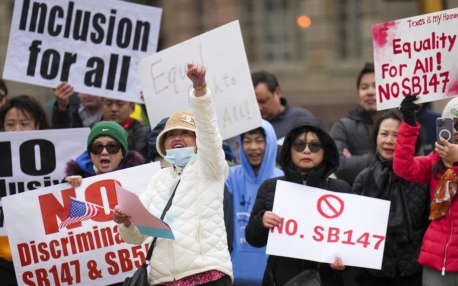 Mingling Huang (in white) raises a fist as she yells in agreement with a speaker during a rally in opposition to Texas Senate Bills 147 and 552 on Sunday, Jan. 29, 2023, in Dallas. 