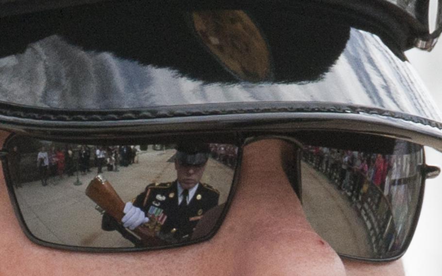 The Changing of the Guard at the Tomb of the Unknown Soldier in Arlington National Cemetery during Medal of Honor Day, March 25, 2016. Reflected on the left sunglass lense, another Guard inspects his rifle. Reflected in the right lense, the crowd watches.