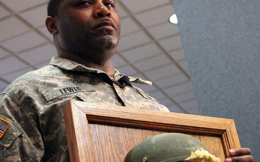 Staff Sgt. Thalamus Lewis poses with the battle-scarred Advanced Combat Helmet he received during a ceremony on April 19, 2016 at Fort Belvoir, Va. The ACH protected him from a bullet wound to the head after insurgents attacked his convoy in Afghanistan in 2012.