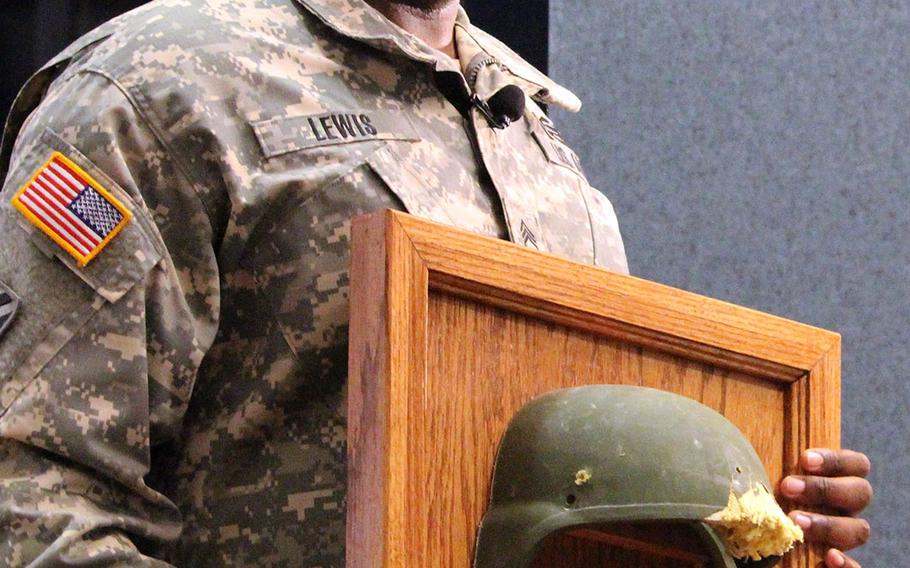 Staff Sgt. Thalamus Lewis poses with the battle-scarred Advanced Combat Helmet he received during a ceremony at Fort Belvoir. The ACH protected him from a bullet wound to the head after insurgents attacked his convoy in Afghanistan in 2012.