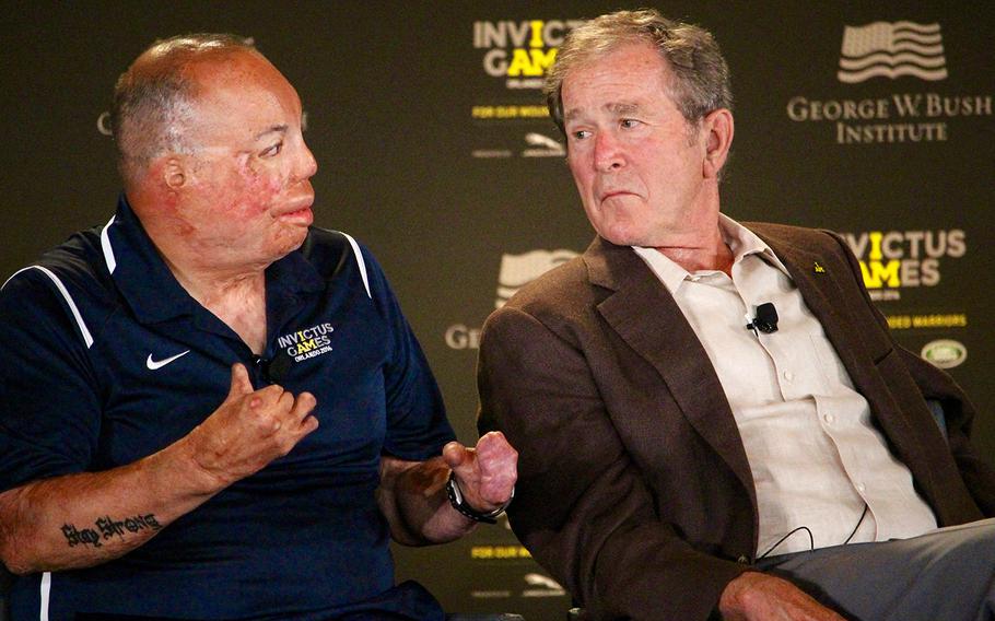 Master Sgt. Israel Del Toro, Jr. talks about complications servicemen face after traumatic injuries as former President George W. Bush listens during the 2016 Invictus Games Symposium on Invisible Wounds, Sunday, May 8, 2016 at Orlando, Fla.