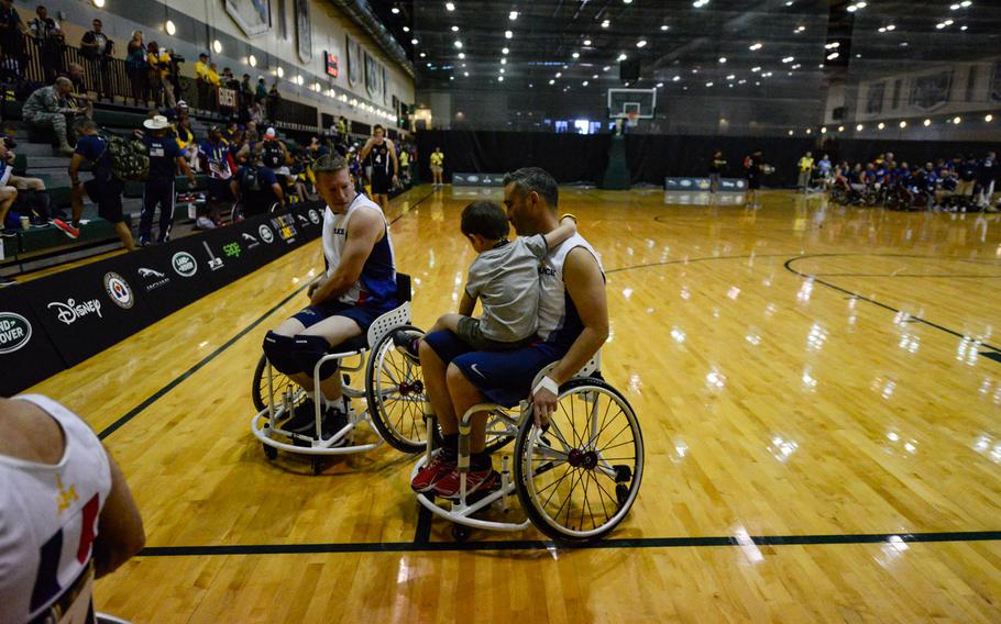 French Marine Herve Labarta holds his 8-year-old son Peio after a preliminary wheelchair basketball game at the Invictus Games 2016, May 6, 2016, Orlando, Fla.