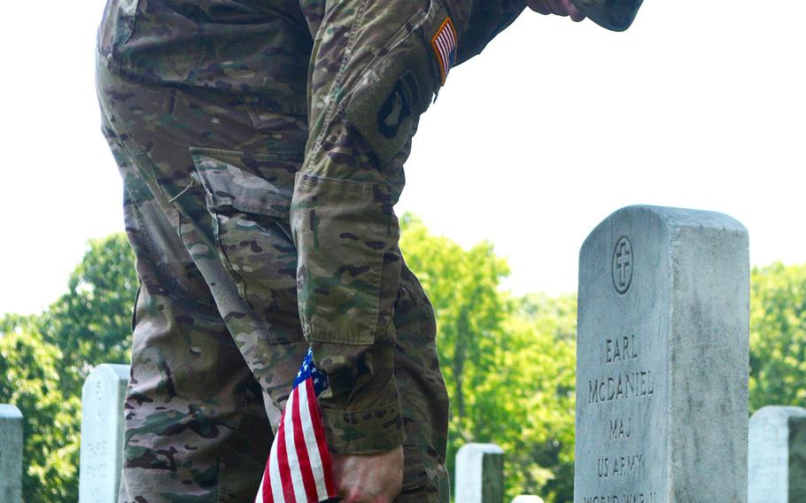 Capt. Andrew McDaniel places a flag at the grave of his grandfather, Maj. Earl McDaniel, during Flags In at Arlington National Cemetery, May 26, 2016.