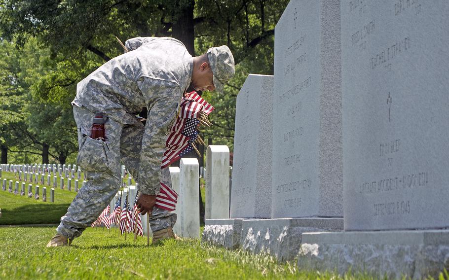 Capt. Rowan Pruitt places an American flag at a headstone in Arlington National Cemetery during Flags In at Arlington National Cemetery on May 26, 2016. 