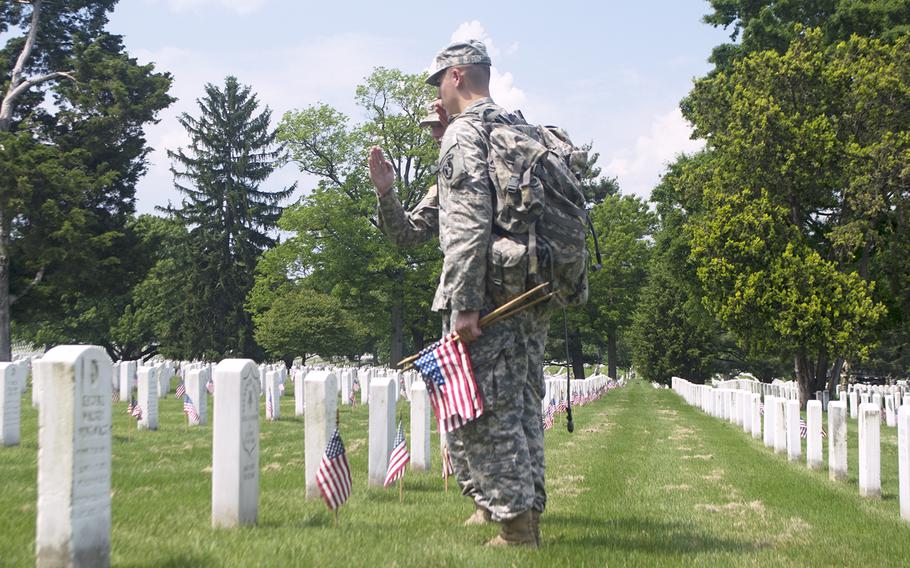 Spc. Marvin Parrish, far left, and Spc. Travis Zapata salute the headstone of Medal of Honor recipient Alexander Jardine. Jardine, who served in the Navy, received the medal due to his actions in the Spanish American War.