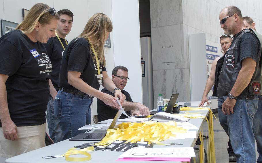 Volunteers for Mindful Memorial Day go over a list of servicemembers killed in action since Sept. 11, 2001, to give ribbons to visitors to the memorial.