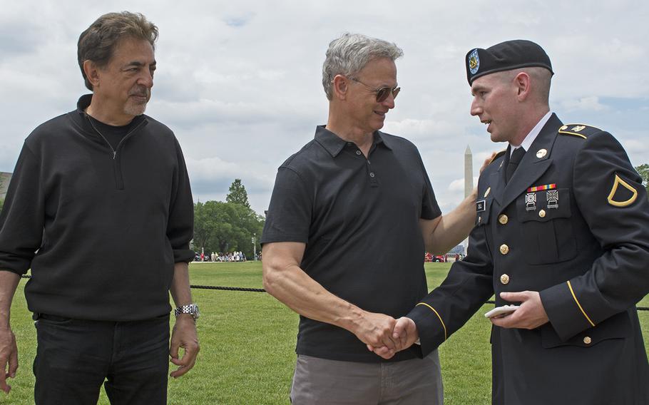 A servicemember shakes hands with actor Gary Sinese before shaking hands with actor Joe Mantegna before the start of the 2016 Memorial Day Parade in Washington, D.C.