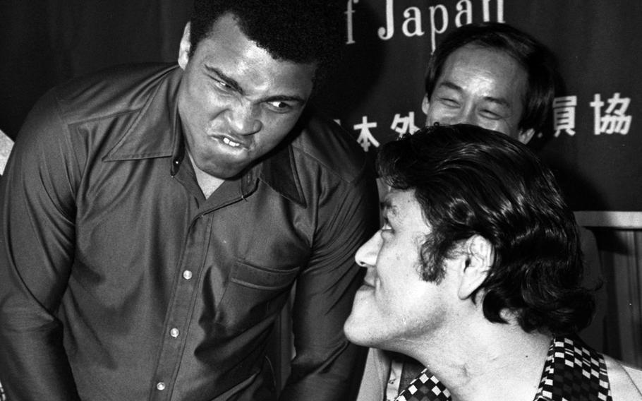 Muhammad Ali scowls at his next opponent, wrestler Antonio Inoki, during a luncheon at the Foreign Correspondents Club of Japan in June, 1976. In the background is Jun Rhee, a Korean taekwondo expert who was said to be teaching karate to Ali in preparation for the exhibition event that would be called "unusual" by the more generous and "a farce" by others.