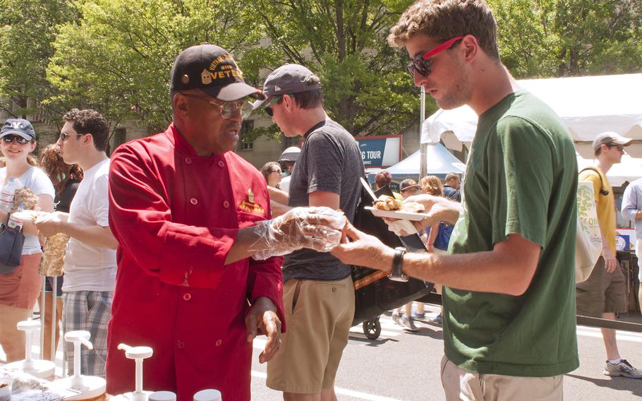 Master Gunnery Sgt. Jeremiah Burn, chef for the USMC, hands out sample fare during the Military Chef Cook-Off - part of the Annual Giant National Capital Barbecue Battle - in Washington, D.C., on June 25, 2016.