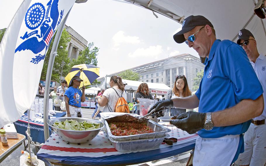 In this shot taken with a wide-angle lense, the U.S. Coast Guard serve up some fare during the Military Chef Cook-Off - part of the Annual Giant National Capital Barbecue Battle - in Washington, D.C., on June 25, 2016. The Coast Guard was the last service in line, competing against the Army, Navy, Air Force and Marines. The voting containers were located behind the white Coast Guard flag.