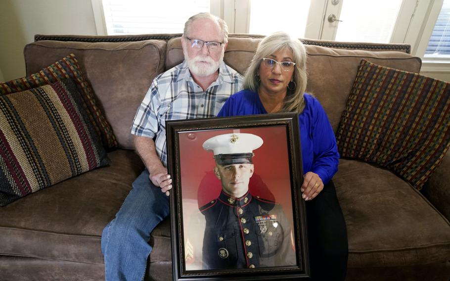 Joey and Paula Reed pose for a photo with a portrait of their son Marine veteran and Russian prisoner Trevor Reed at their home in Fort Worth, Texas, Tuesday, Feb. 15, 2022. Russia is holding Trevor Reed, who was sentenced to nine years on charges he assaulted a police officer. 