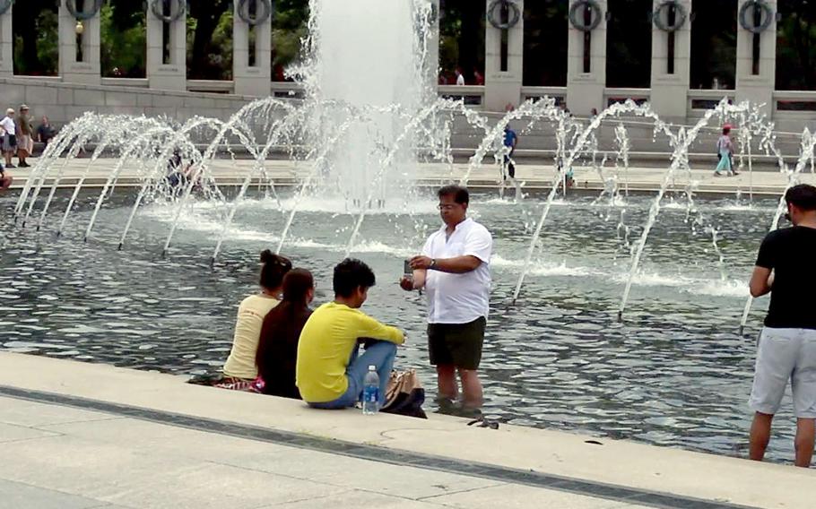 Abdul Silah takes a picture of his kids while immersed in water at the pool at the World War II Memorial at the National Mall in Washington, D.C., on July 21, 2016.
