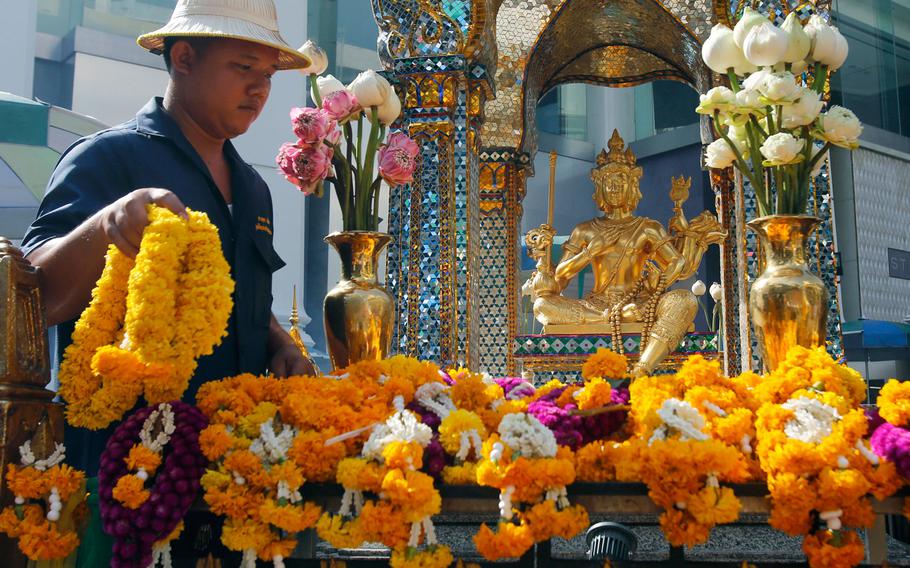 An Erawan Shrine staff member organizes garlands visitors laid at Phra Phrom, the Thai interpretation of the Hindu god Brahma, at the Erawan Shrine in Bangkok, Thailand, Wednesday, Aug. 17, 2016. 