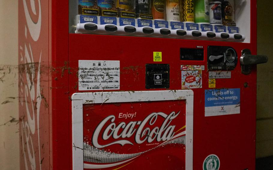 Floodwaters leave a Coca-Cola machine dirty on Yokota Air Base, Japan, Tuesday, Aug. 23, 2016. A flood line from one of the housing towers on the east side of the base shows waters reached about 3 feet. Yokota's drainage system was overwhelmed after 10 inches of rain from Typhoon Mindulle hit the western Tokyo air base Monday afternoon.   