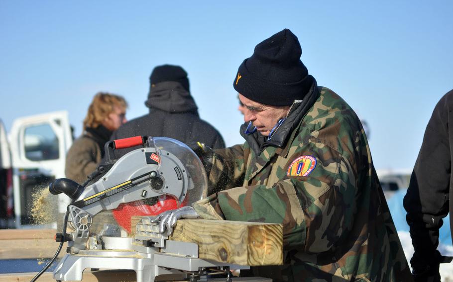 Vietnam War veteran Dan Luker, 66, uses a miter saw to cut boards for barracks veterans helped to build at the Oceti Sakowin protest camp on Saturday, Dec. 3. Lurker said he is a retired carpenter and part Cherokee.