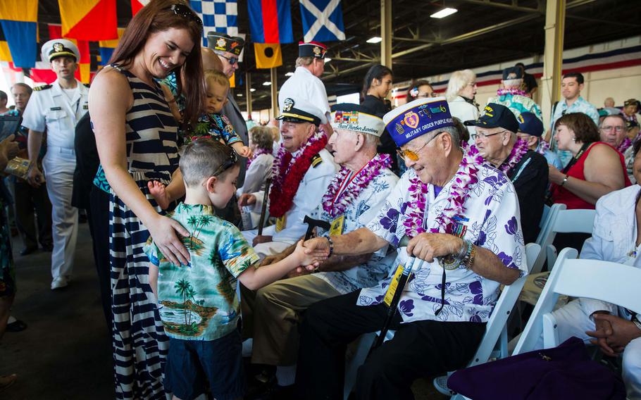 Pearl Harbor survivor Henry N. J. Lee shakes hands with Bryson Brown shortly before the beginning of a ceremony at Joint Base Pearl Harbor-Hickam, Hawaii, to commemorate the attack 75 years ago, Wednesday, Dec. 7, 2016. Seated near Lee are Pearl Harbor survivors Lou Conter, center, and Fred Smith.
