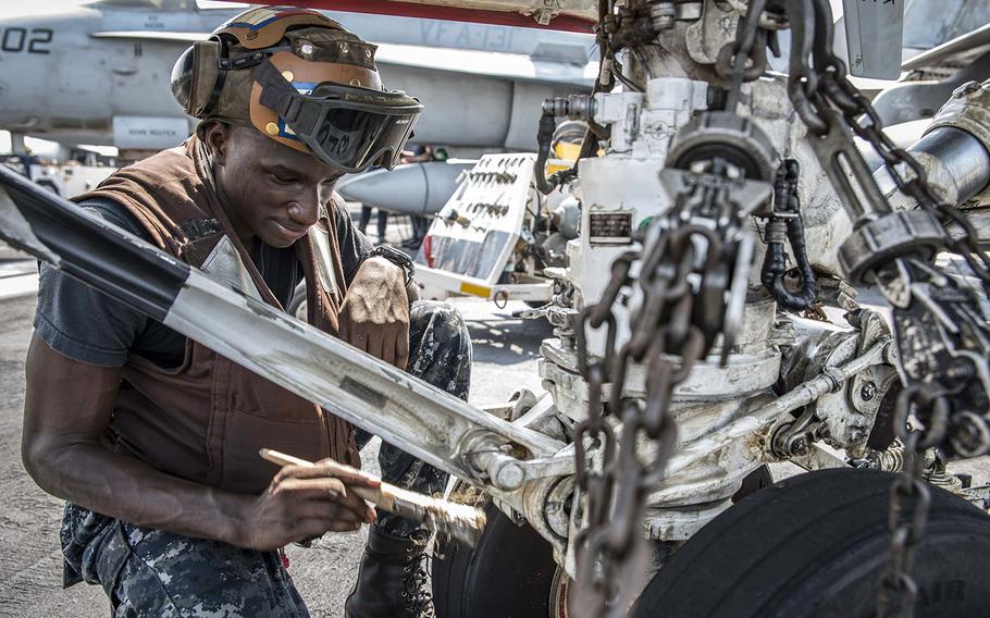 In a September, 2016 file photo, Airman Holguy Rinchet cleans the landing gear of an F/A-18C Hornet assigned to Strike Fighter Squadron 131 on the flight deck of the aircraft carrier USS Dwight D. Eisenhower in the Persian Gulf.