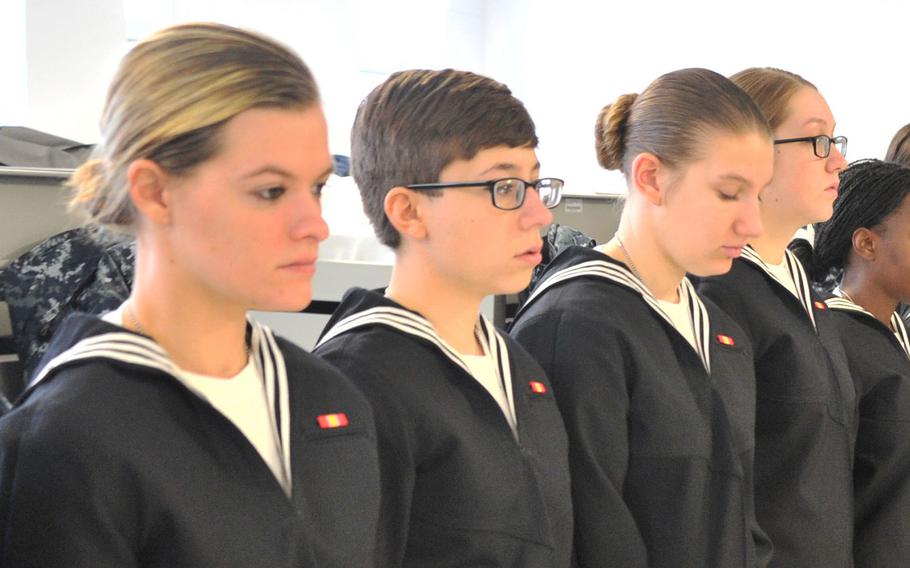 Recruits from Division 904 are standing in front of their beds in their new dress uniform during tailor two fitting visit from Navy Exchange Uniform Issue employees at Recruit Training Command, Nov. 10, 2016.