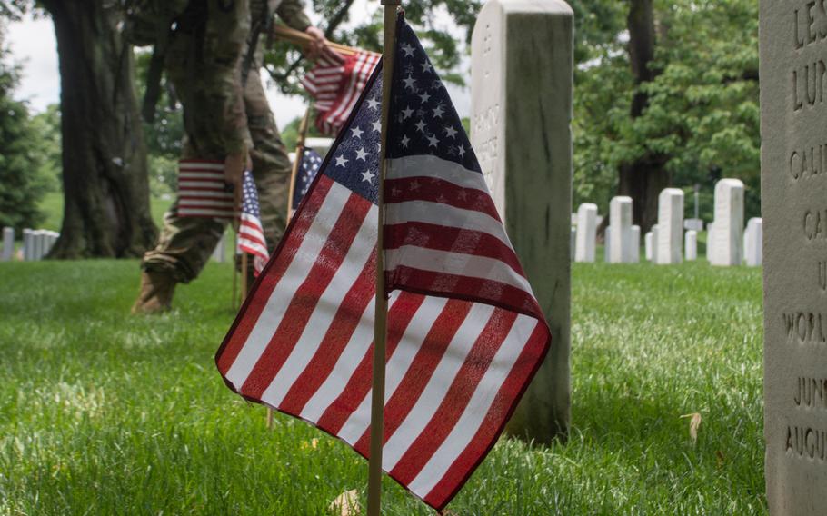 A soldier with the 3rd U.S. Infantry Regiment (The Old Guard) places a flag at Arlington National Cemetery during Flags In on May 25, 2017.