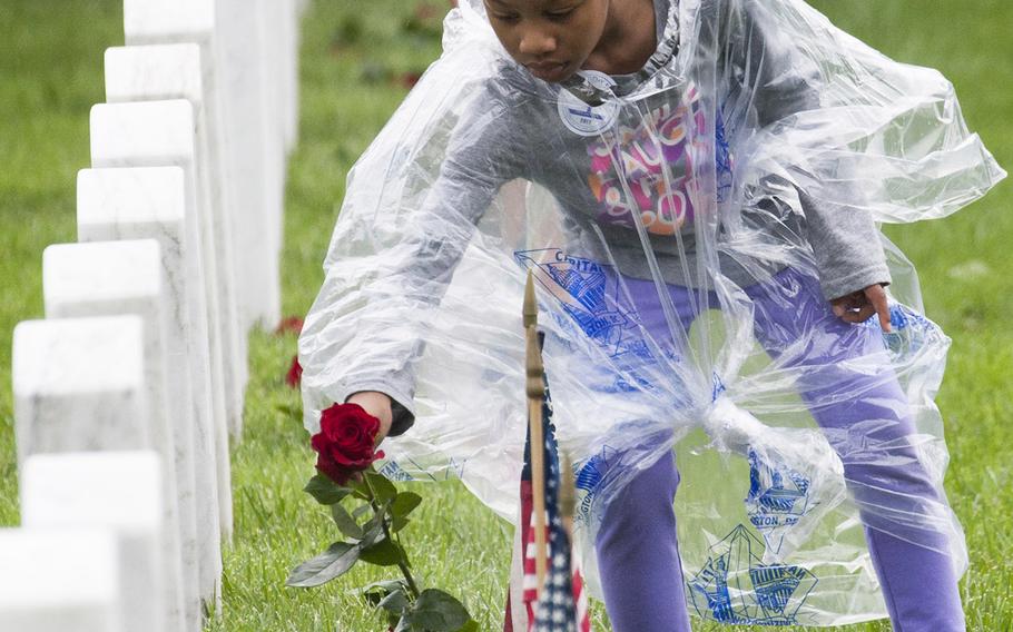 Six-year-old Liana Danner places a rose at an Arlington National Cemetery grave during an event organized by the Memorial Day Flowers Foundation on Sunday, May 28, 2017.