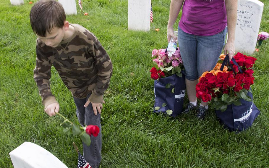 Volunteers place roses at an Arlington National Cemetery grave during an event organized by the Memorial Day Flowers Foundation on Sunday, May 28, 2017.