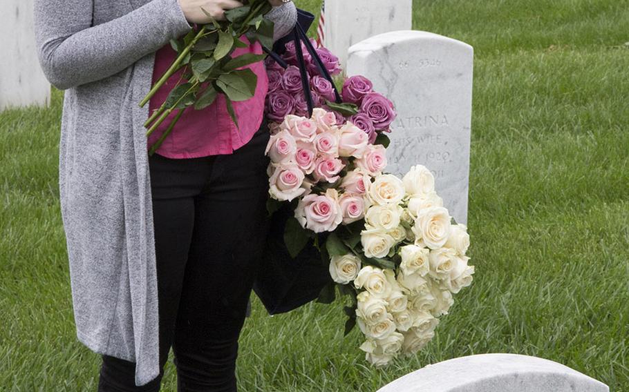 Cathleen Beckman pauses before placing a rose at an Arlington National Cemetery grave during an event organized by the Memorial Day Flowers Foundation on Sunday, May 28, 2017.