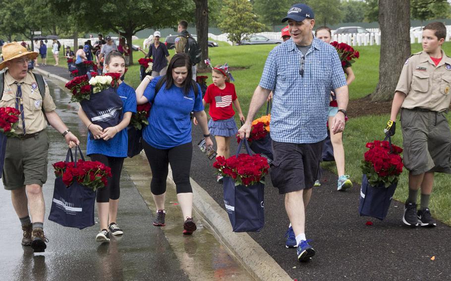 Volunteers carry bags of roses to be placed at Arlington National Cemetery graves during an event organized by the Memorial Day Flowers Foundation on Sunday, May 28, 2017.