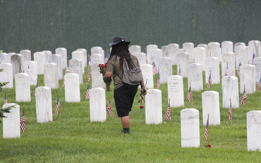 A vlunteer walks through a sudden downpour to place roses on Arlington National Cemetery graves during an event organized by the Memorial Day Flowers Foundation on Sunday, May 28, 2017.