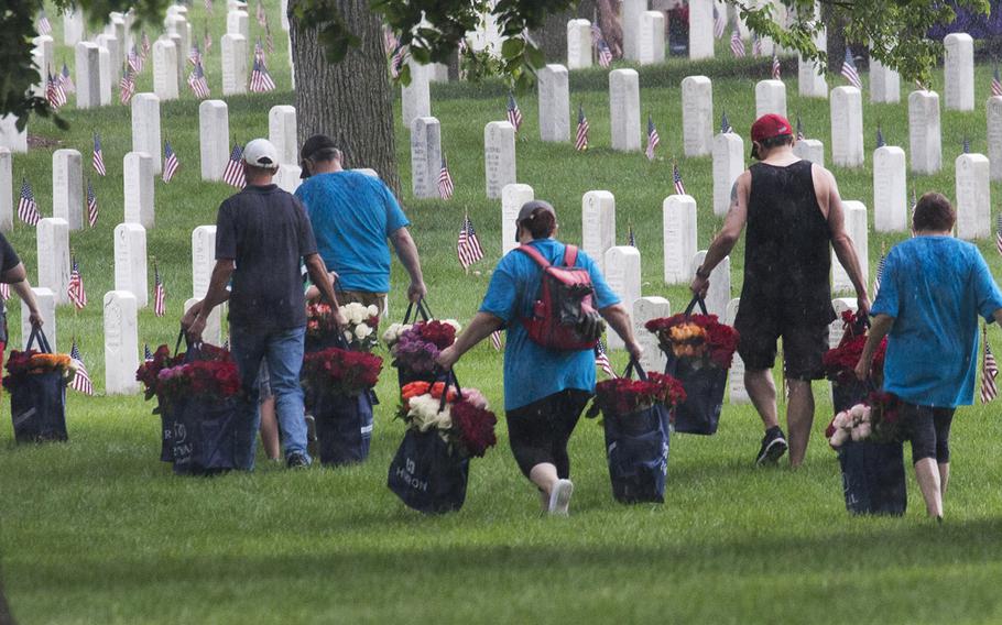 Volunteers carry bags of roses to be placed at Arlington National Cemetery graves during an event organized by the Memorial Day Flowers Foundation on Sunday, May 28, 2017.