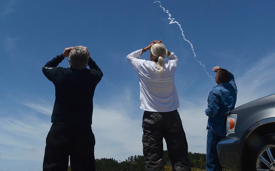 Spectators watch an interceptor missile launch from an underground silo at Vandenberg Air Force Base in California and fly toward an intercontinental-range missile fired from a test range on Kwajalein Atoll in the Pacific.