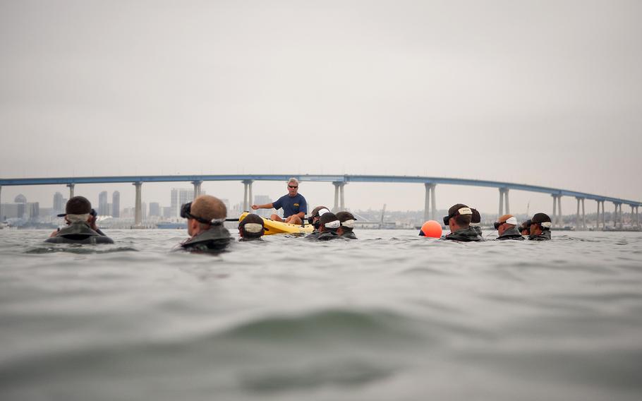 An instructor from Naval Special Warfare Training Center, at Naval Amphibious Base Coronado, briefs Basic Underwater Demolition/SEAL (BUD/S) students before they participate in interval swim training in San Diego Bay. 