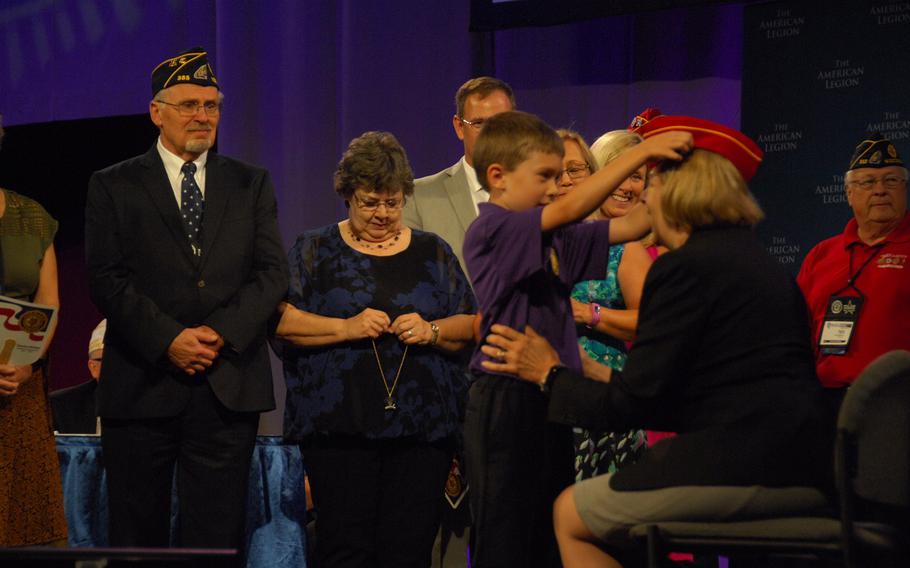 Denise Rohan, right, sits as her grandson, Sawyer, places her new cap on her head onstage during the American Legion National Convention in Reno, Nev. on Thursday, Aug. 24. Rohan was elected to be the group's new national commander.