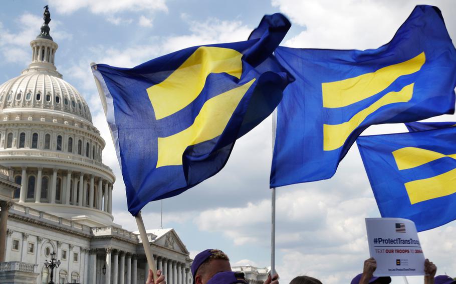 In this July 26, 2017 file photo, people with the Human Rights Campaign hold up "equality flags" during an event on Capitol Hill in Washington, in support of transgender members of the military.