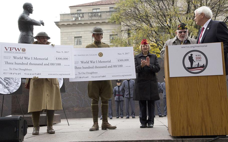 Terry Hamby, right, chairman of the U.S. World War I Centennial Commission, watches as ceremonial checks marking contributions from the Veterans of Foreign Wars and the American Legion are displayed during groundbreaking ceremonies for the National World War I Memorial in Washington, D.C.'s Pershing Park, November 9, 2017. With him are American Legion National Commander Denise H. Rohan and VFW Commander in Chief Keith Harman.