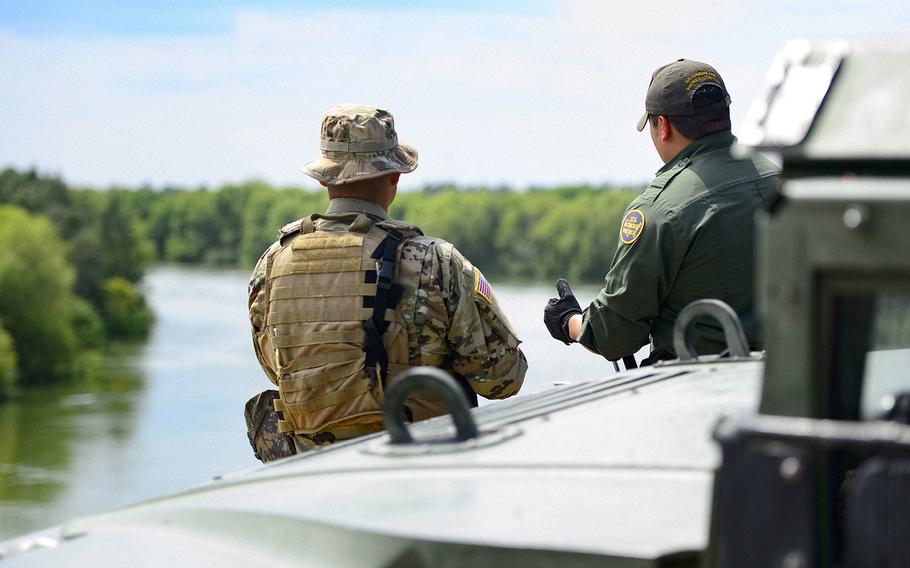 A Texas Guardsman and a Customs and Border Patrol agent stand near the shores of the Rio Grande River in Starr County, Texas as part of the federal call-up to the Texas Mexico border in April 2018. 