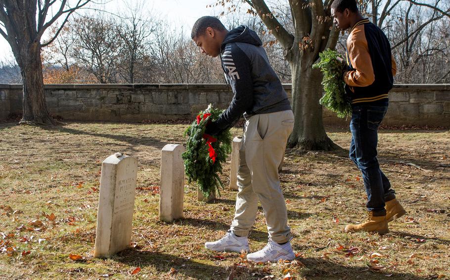 Volunteers Trevor Anderson, left, and Elijah Jones place wreaths at the graves of six African-American soldiers during Wreaths Across America at Antietam National Cemetery in Sharpsburg, Md., December 16, 2017. Both will be joining the Marine Corps in January.