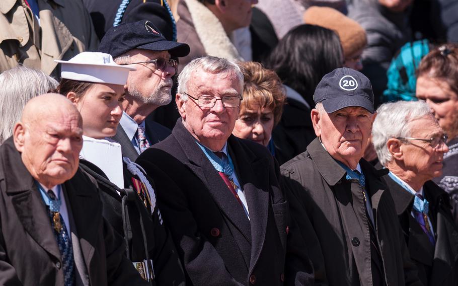 A crowd of onlookers, including more than two dozen Medal of Honor recipients, watch an Army sentry perform his guard duties before the start of a special wreath-laying ceremony at Arlington National Cemetery's Tomb of the Unknowns on Friday, March 23, 2018.
