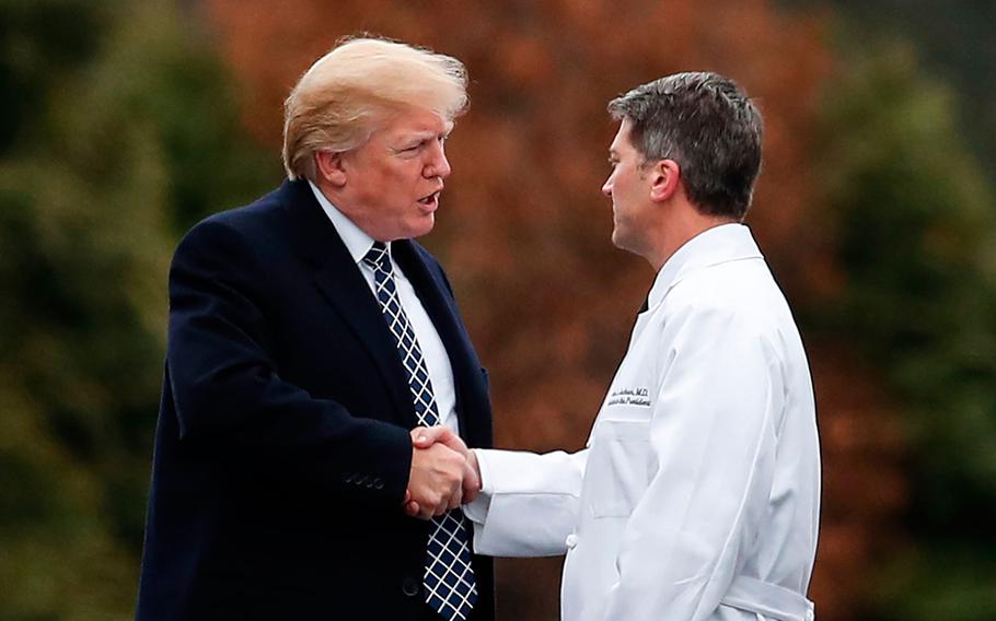 In this Friday, Jan. 12, 2018 file photo, President Donald Trump shakes hands with White House physician Dr. Ronny Jackson as he boards Marine One to leave Walter Reed National Military Medical Center in Bethesda, Md., after his first medical check-up as president. Now it’s Washington’s turn to examine Jackson. The doctor to Presidents George W. Bush, Barack Obama and now Donald Trump is an Iraq War veteran nominated to head the Department of Veterans Affairs.