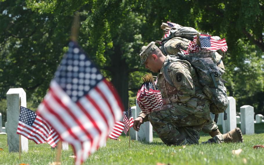 A soldier with the U.S. Army's 3rd Infantry Regiment places a flag at a graveside at Arlington National Cemetery as The Old Guard visited graves throughout the cemetery for Flags In on May 24, 2018. 